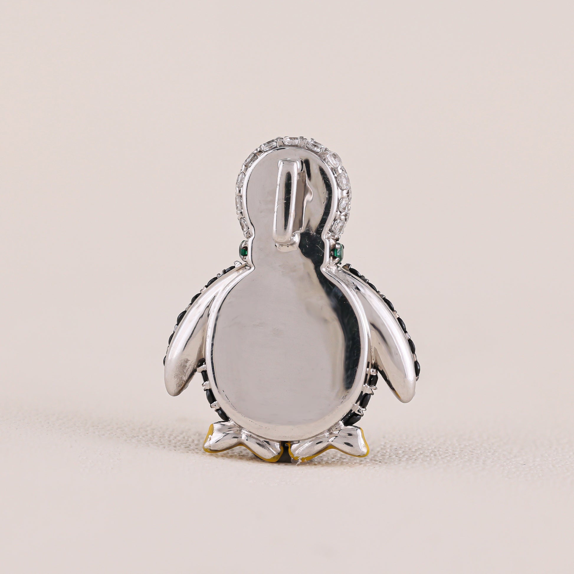 Silver penguin pendant on a beige background