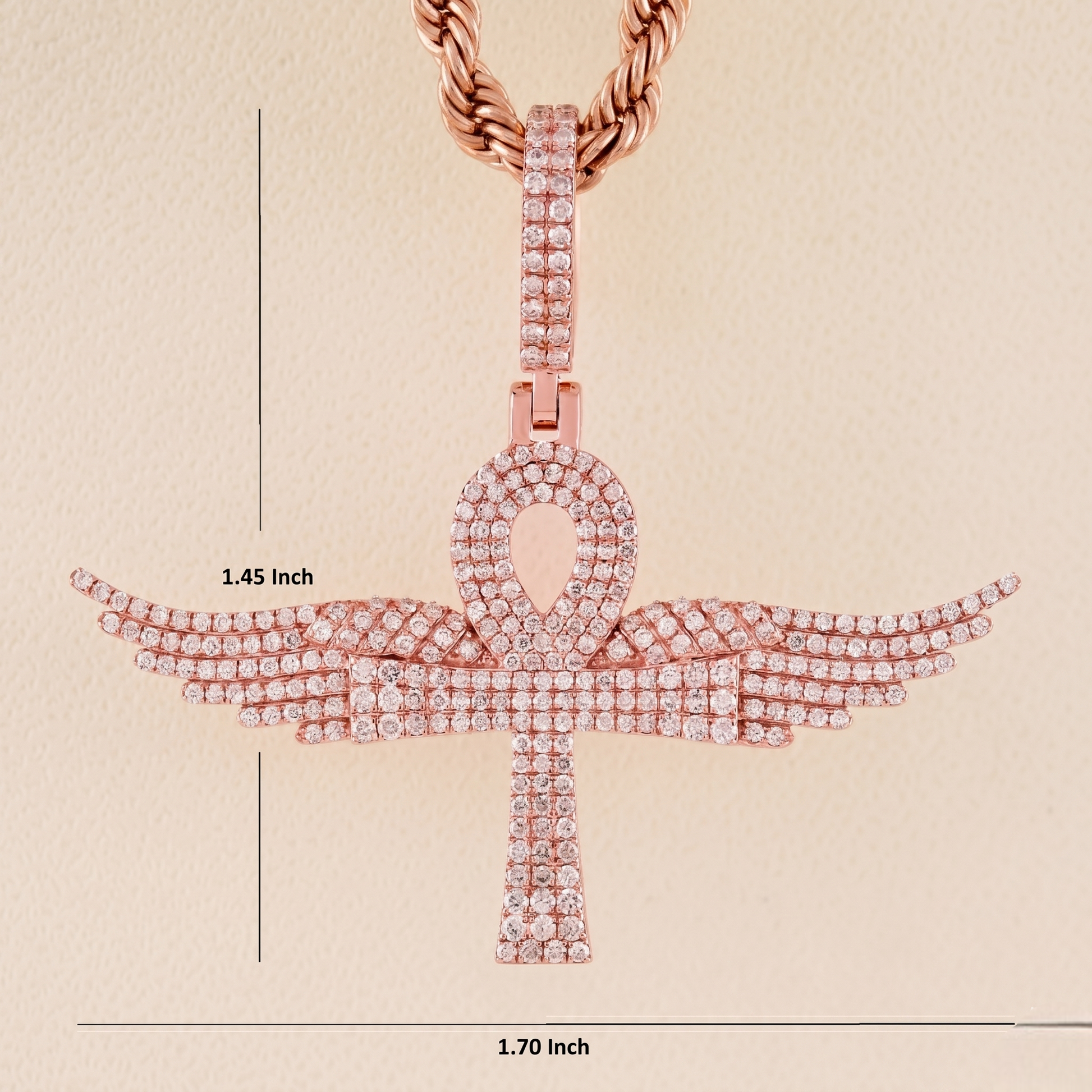 Rose gold ankh pendant with measurements on a beige background