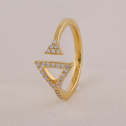 Gold ring with triangular design and embedded diamonds on a beige background