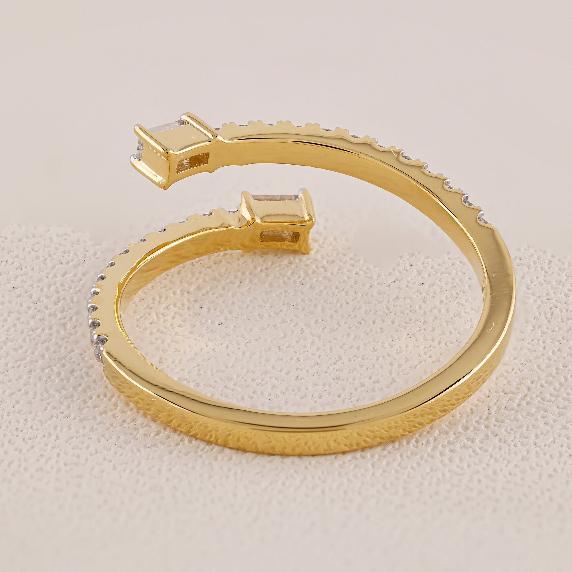 Gold bracelet with embedded stones on a textured beige surface