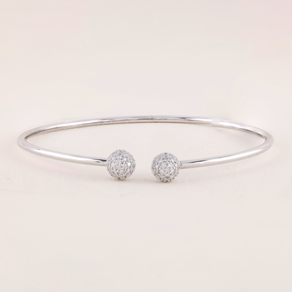 White Gold bracelet with two spherical charms on a light pink background