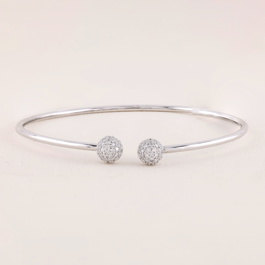 White Gold bracelet with two spherical charms on a light pink background