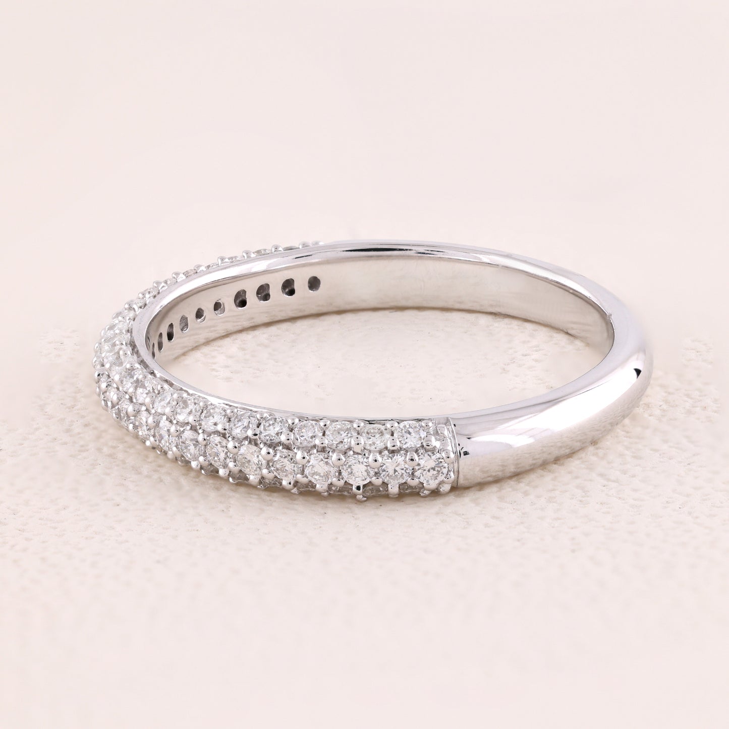 Silver ring with diamond accents on a light pink background