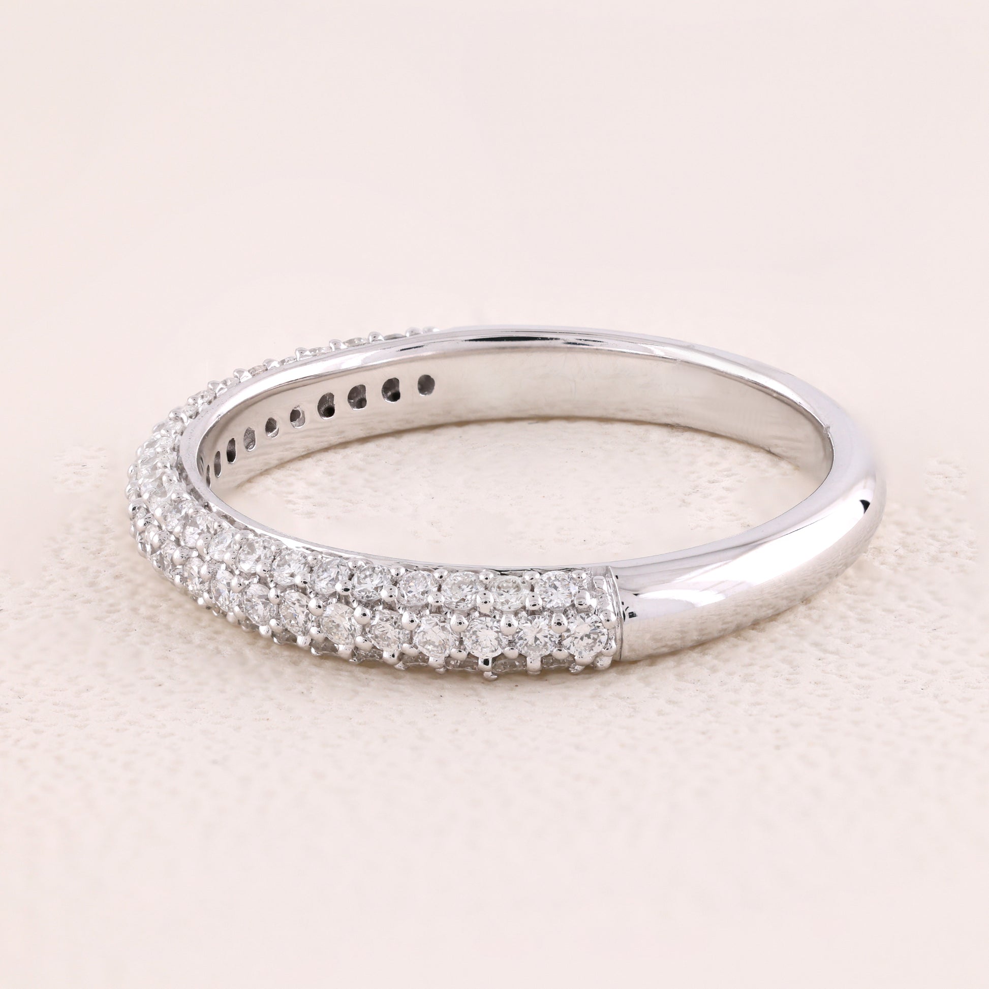 Silver ring with diamond accents on a light pink background