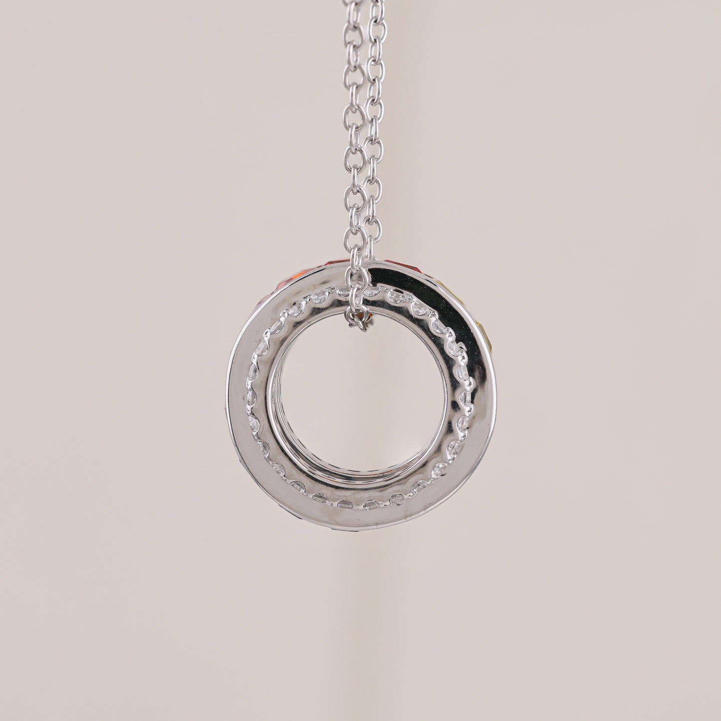 Silver circular pendant necklace on a light beige background