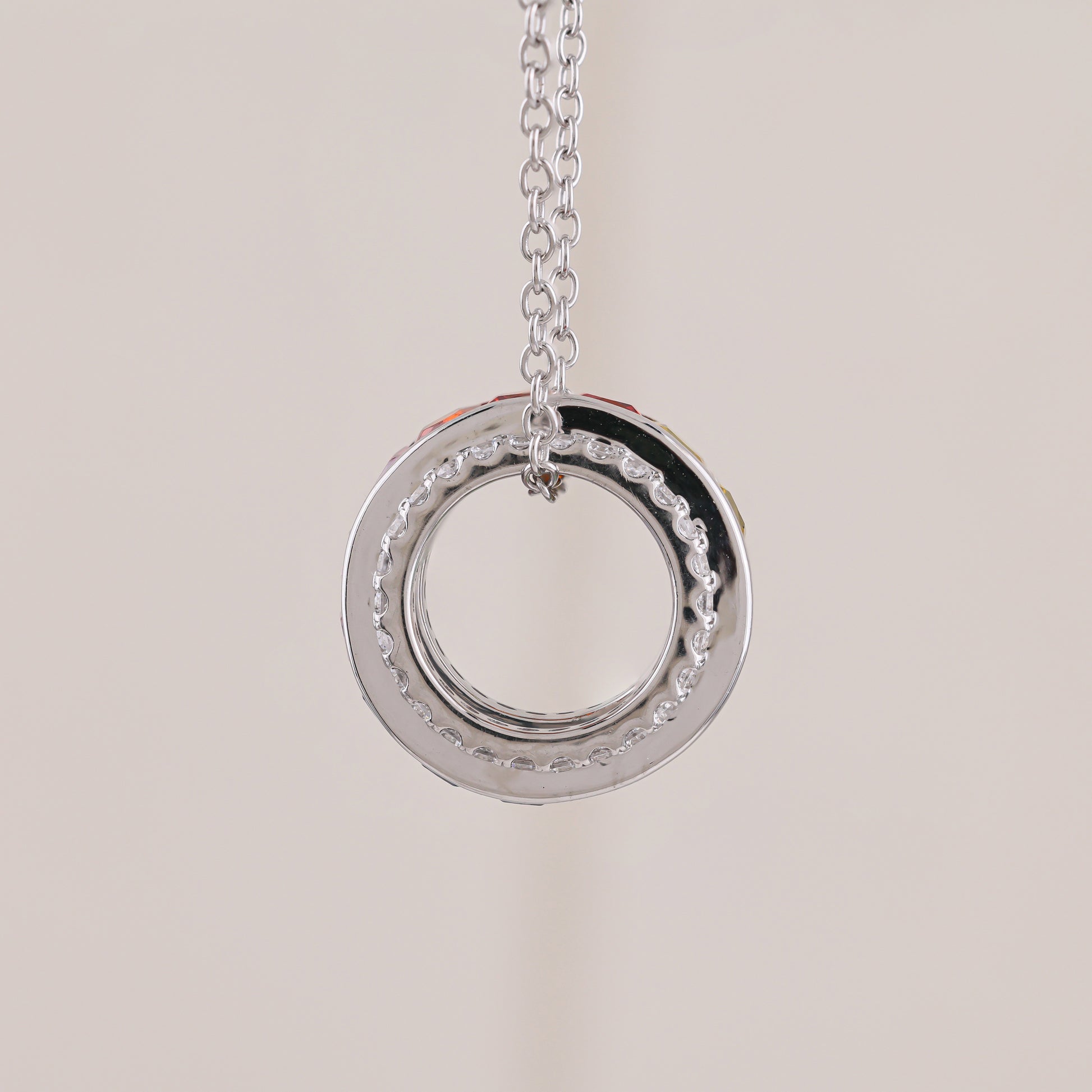 Silver circular pendant necklace on a light beige background