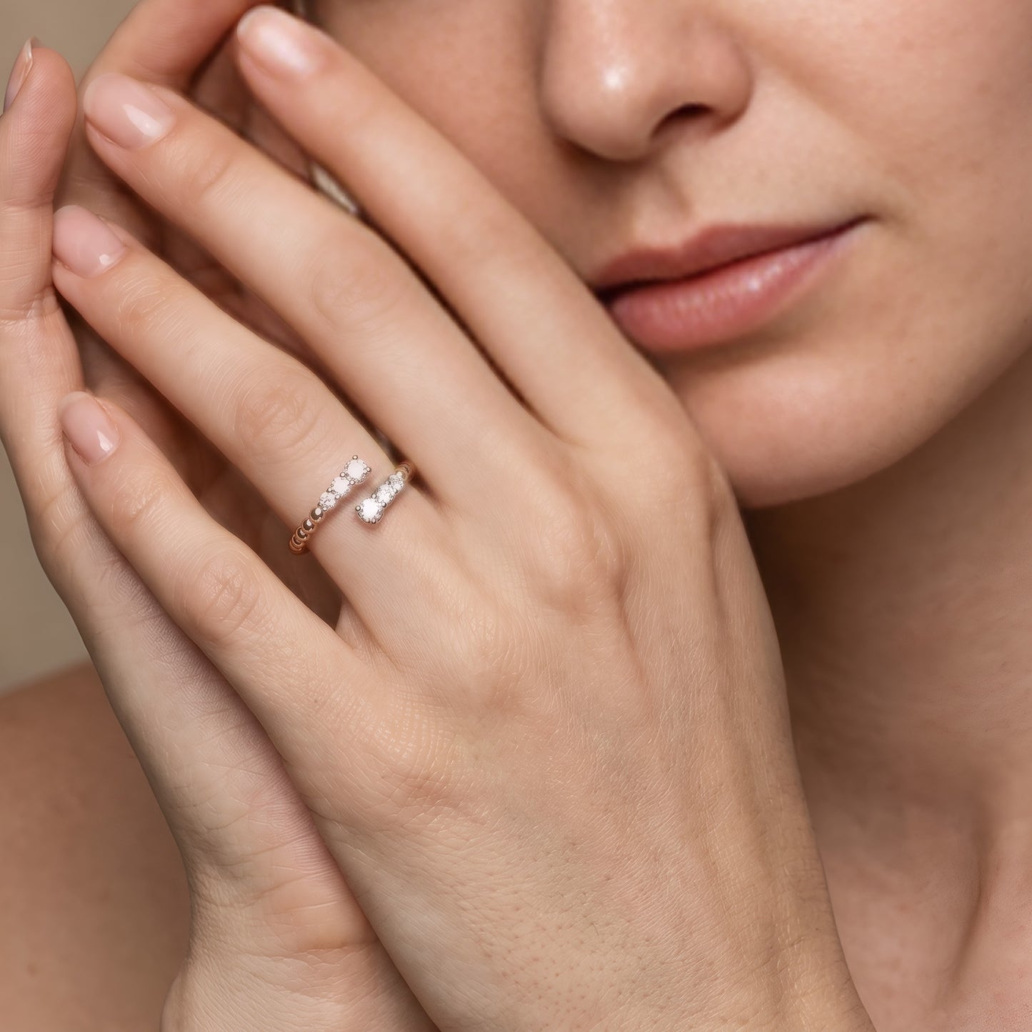 Close-up of a hand wearing a diamond ring with a neutral background
