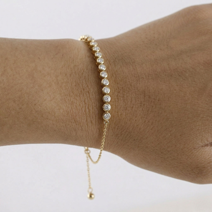 Gold bracelet with small beads on a wrist against a white background