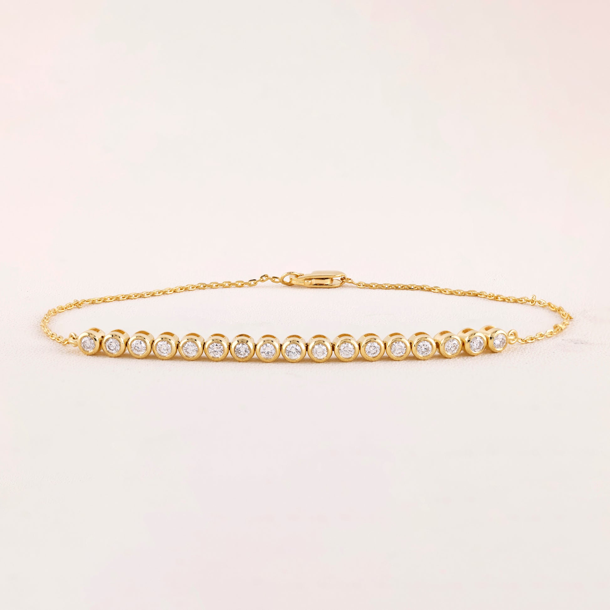 Gold bracelet with diamonds on a light beige background