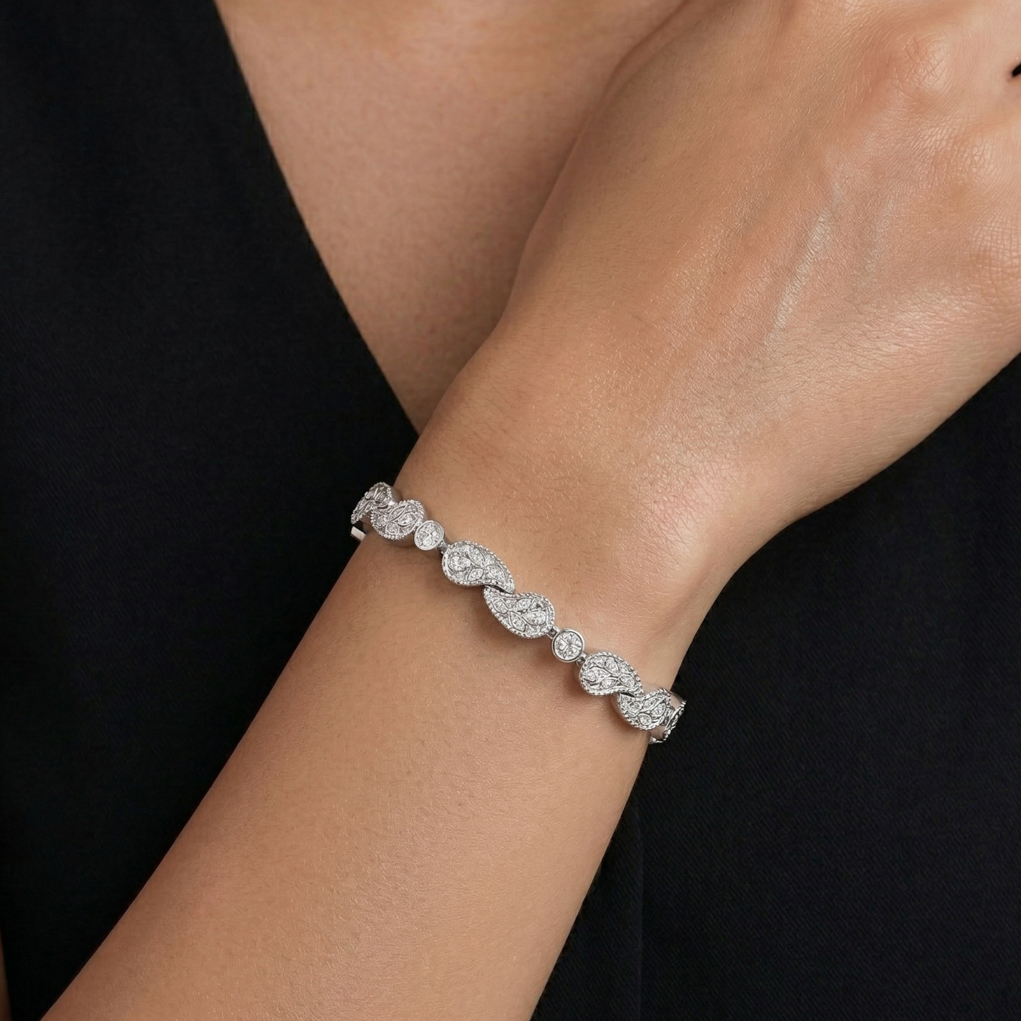 Silver bracelet with marquise-shaped diamonds on a wrist against a black background