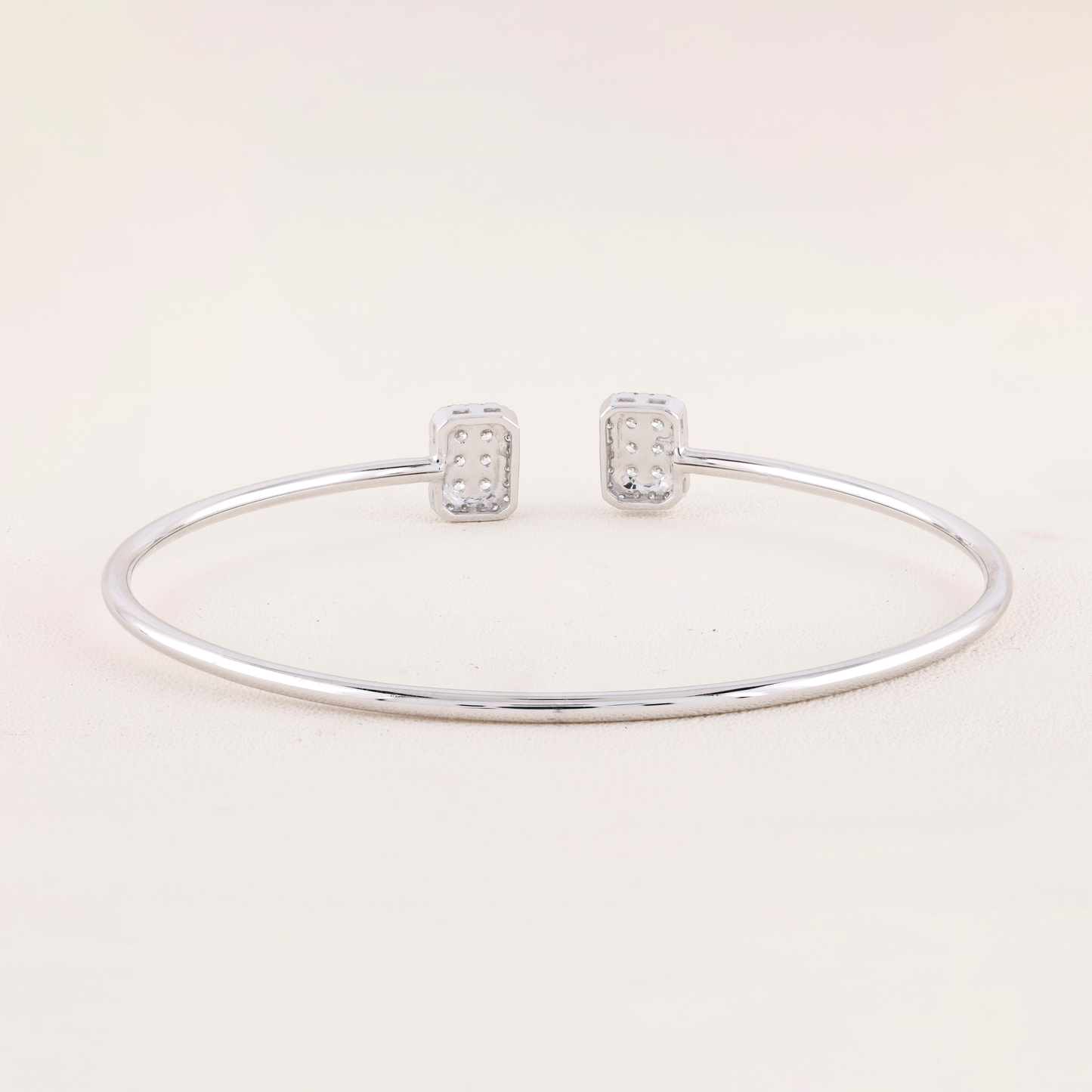 Silver bracelet and earrings on a light pink background
