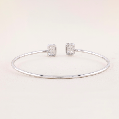 Silver bracelet and earrings on a light pink background