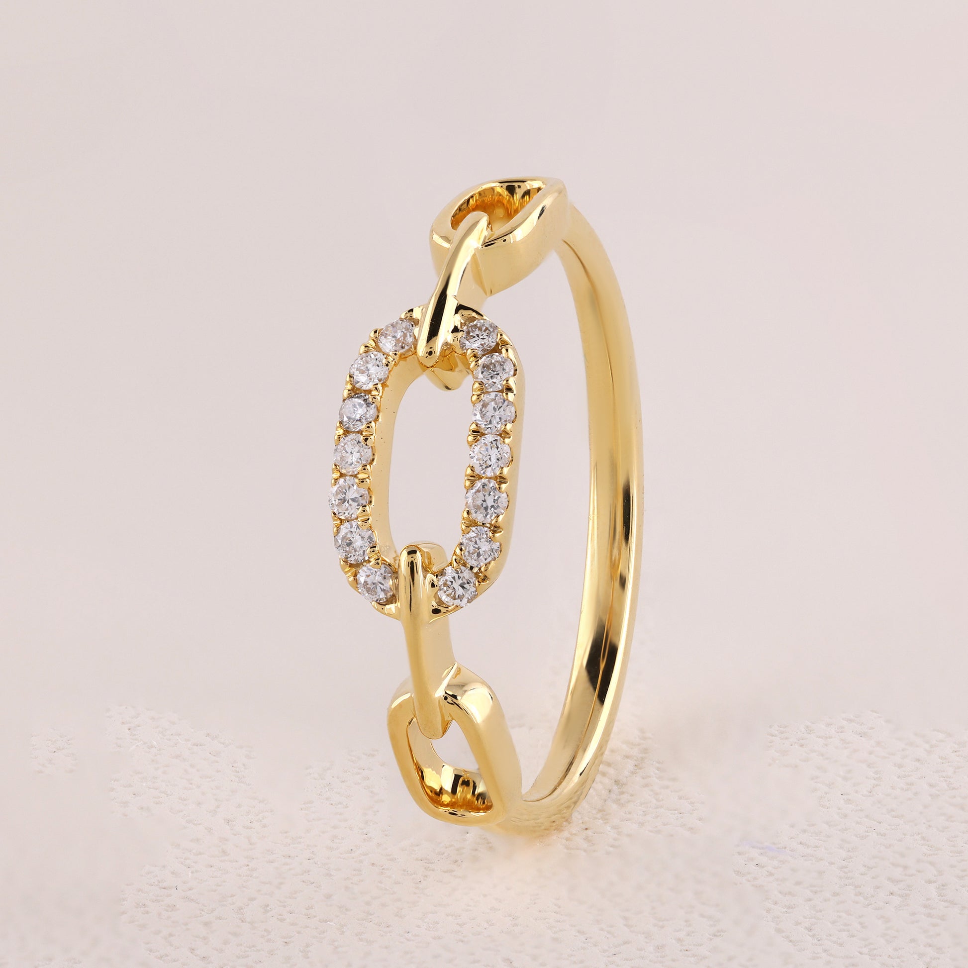 Gold ring with diamond accents on a light pink background