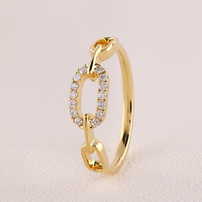 Gold ring with diamond accents on a light pink background