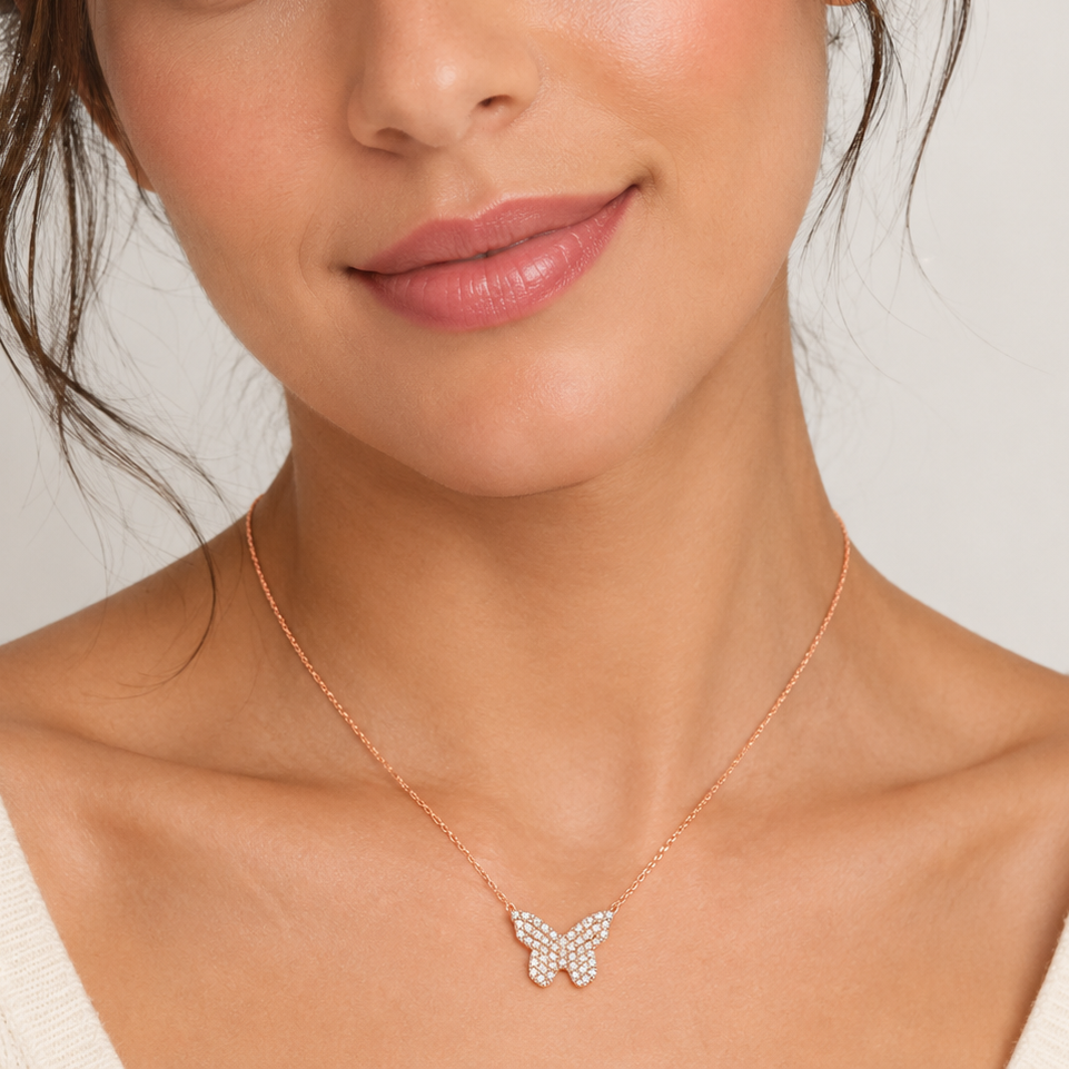 Close-up of a woman wearing a delicate necklace with a butterfly pendant on a neutral background