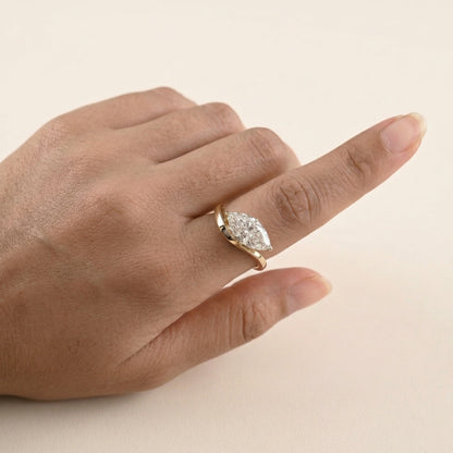 Hand wearing a gold ring with a diamond on a beige background