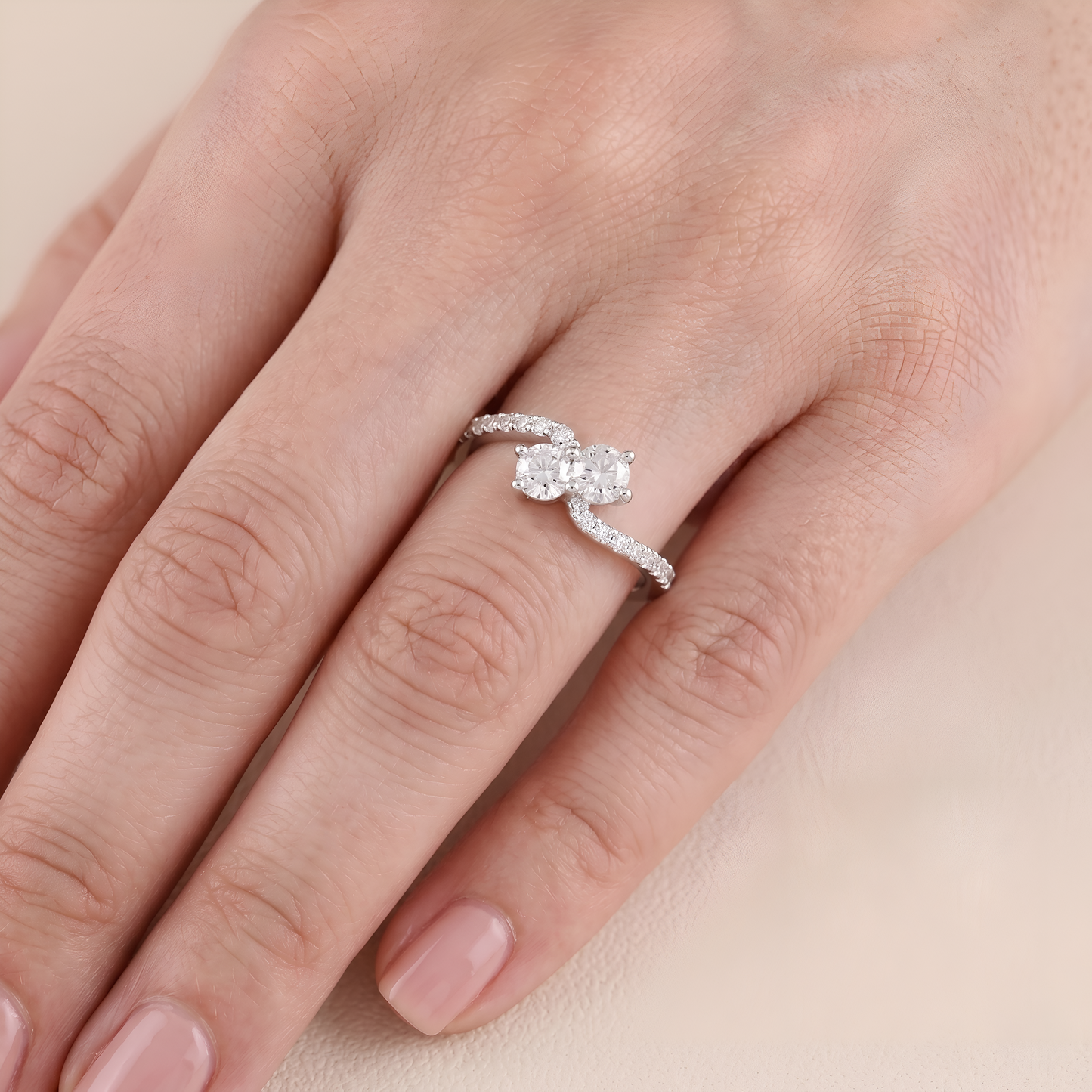 Hand wearing a diamond ring on a beige background