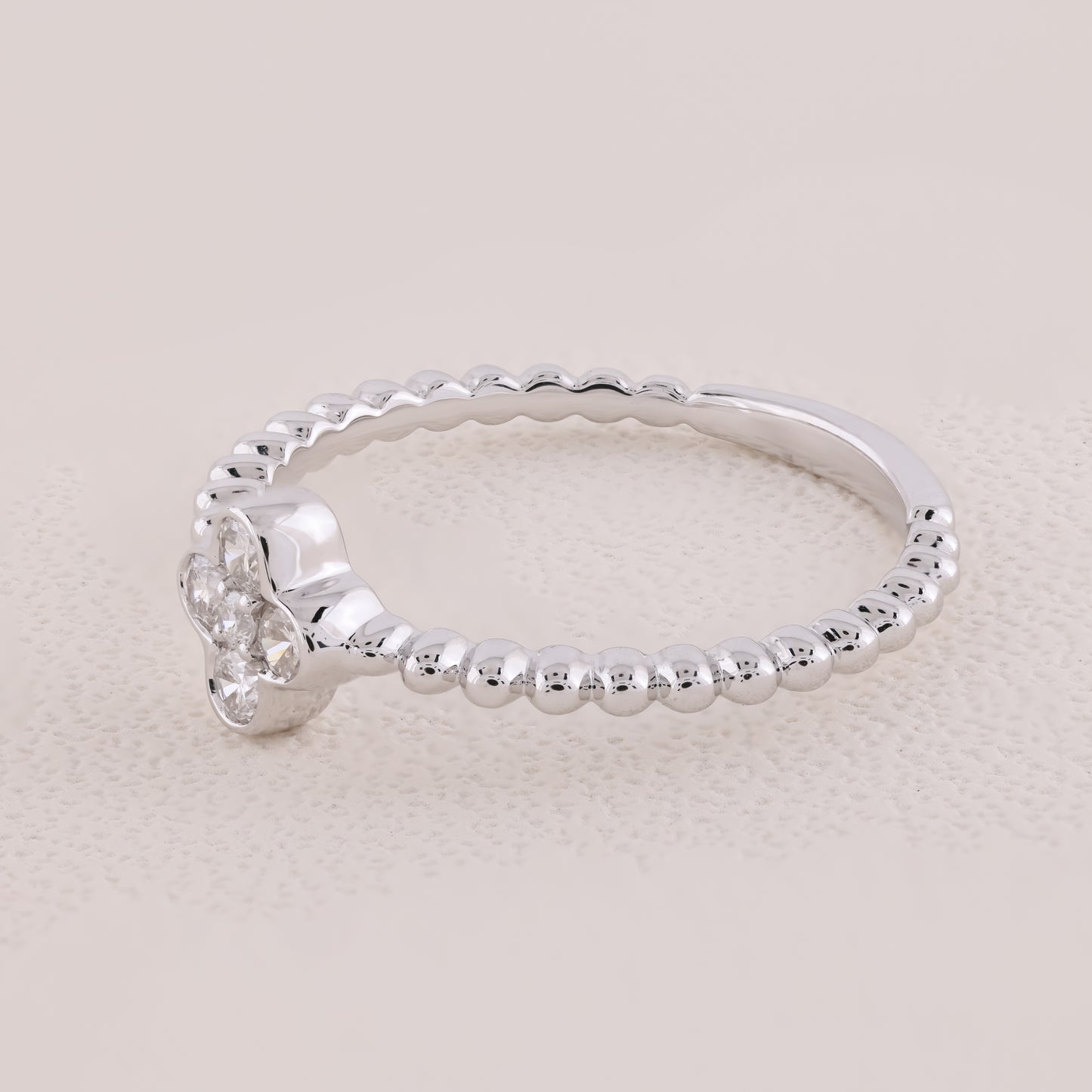 Silver ring with beaded design on a light beige background