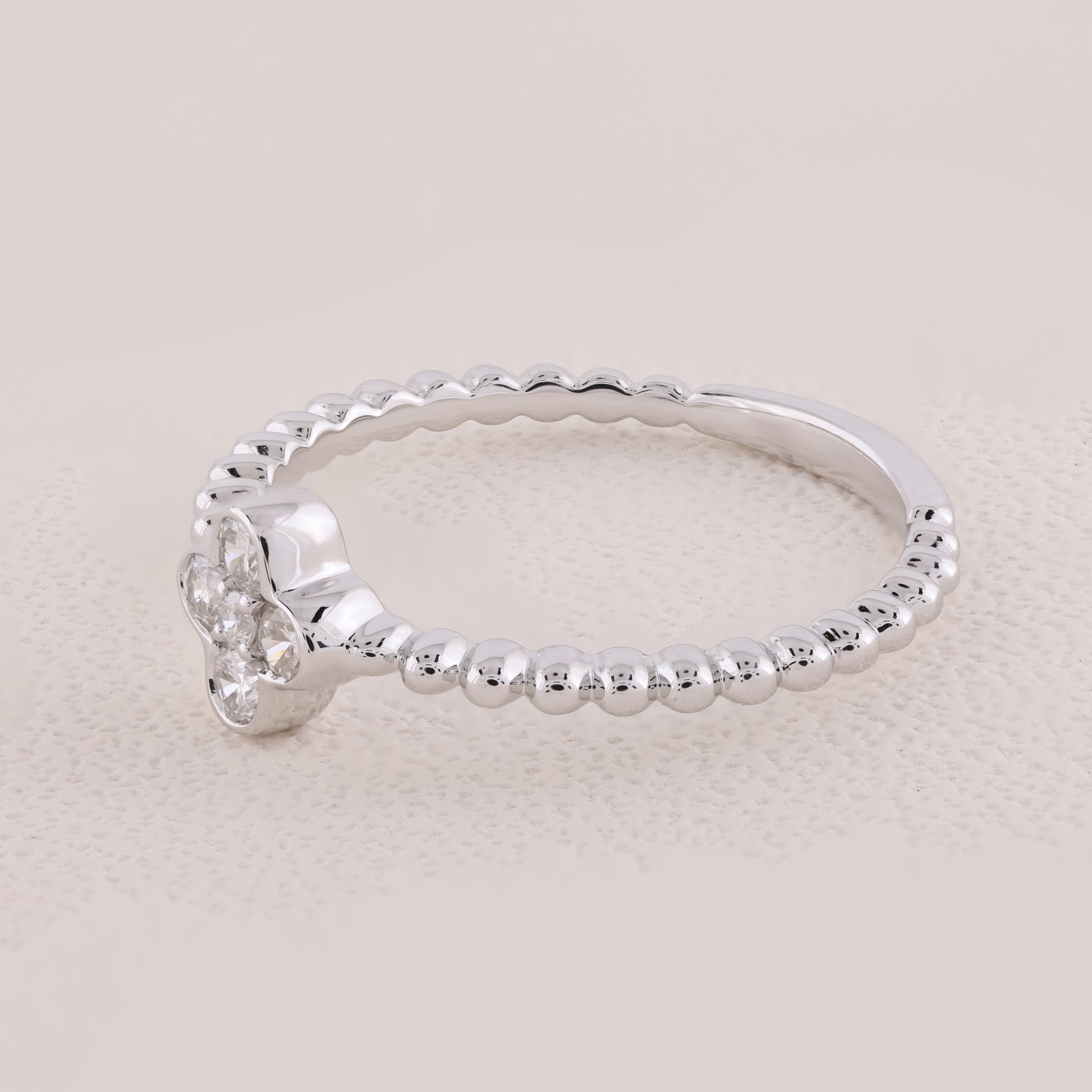 Silver ring with beaded design on a light beige background