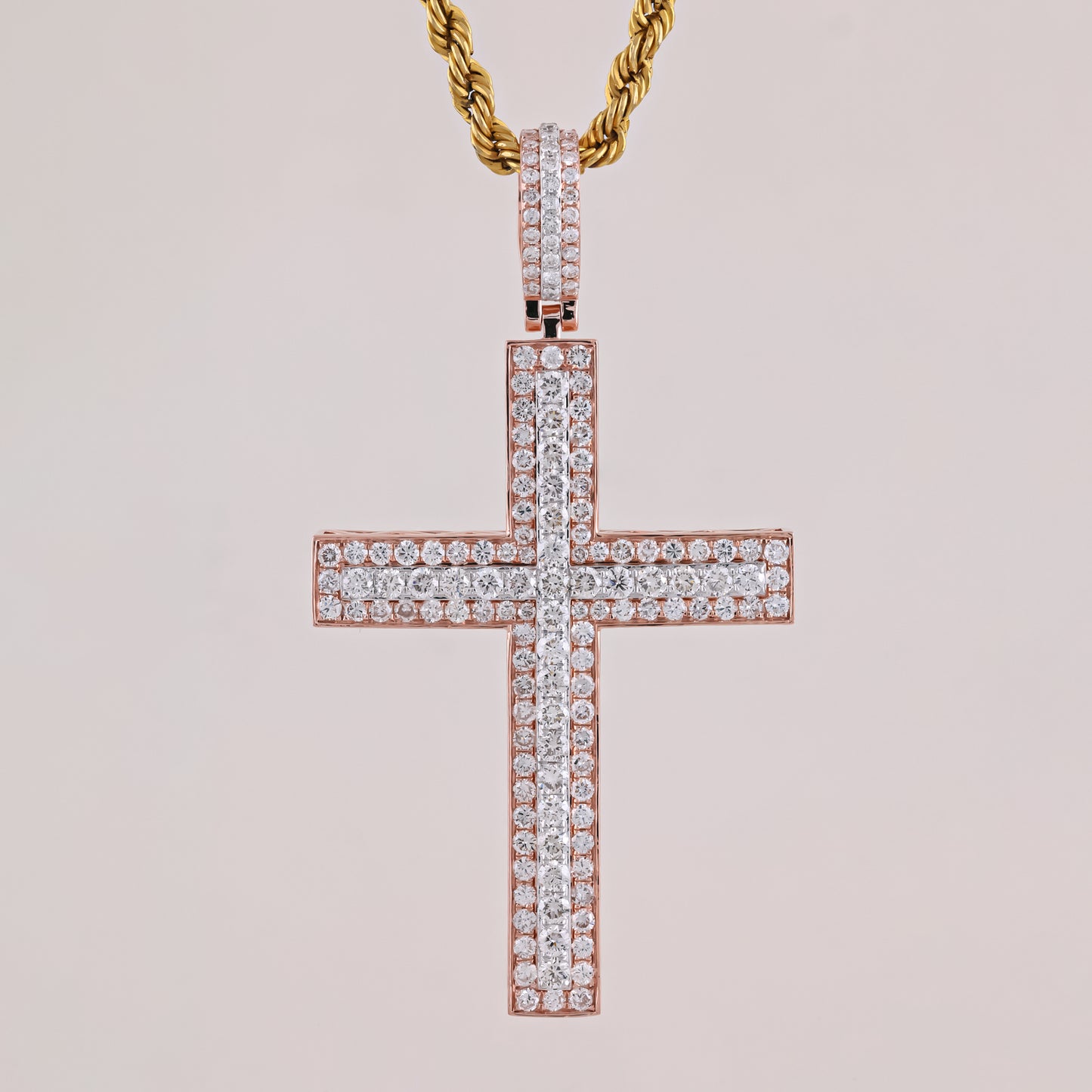 Rose gold cross pendant with diamonds on a light pink background