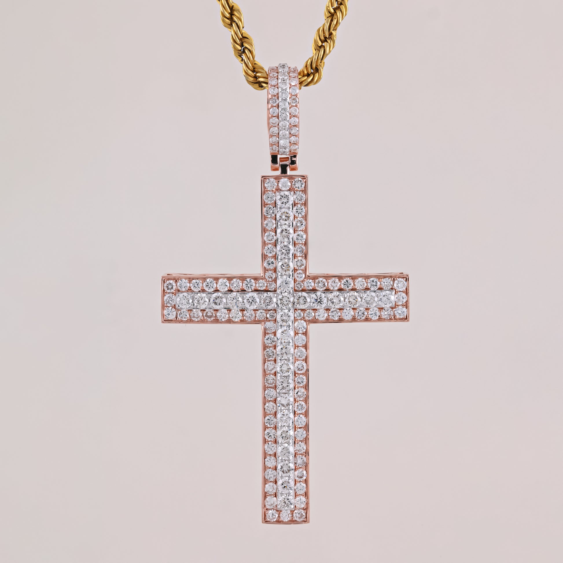 Rose gold cross pendant with diamonds on a light pink background