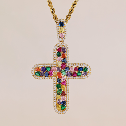 Colorful gemstone cross pendant on a gold chain against a beige background