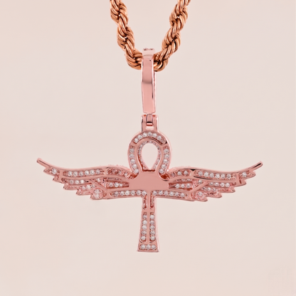 Rose gold pendant with wings on a beige background