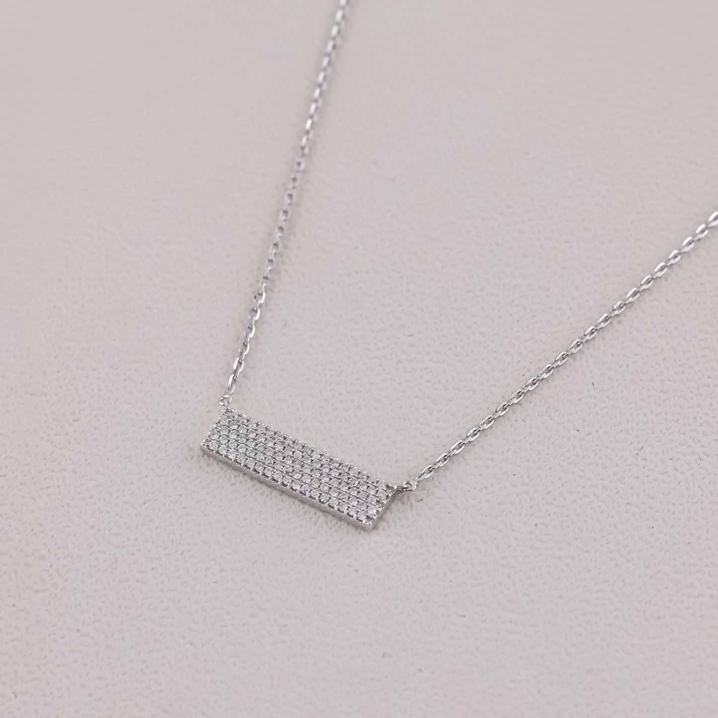 Silver necklace with a rectangular pendant on a light gray background