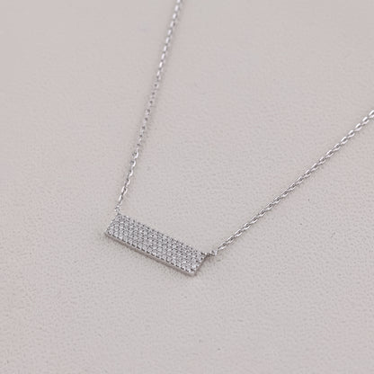 Silver necklace with a rectangular pendant on a light gray background