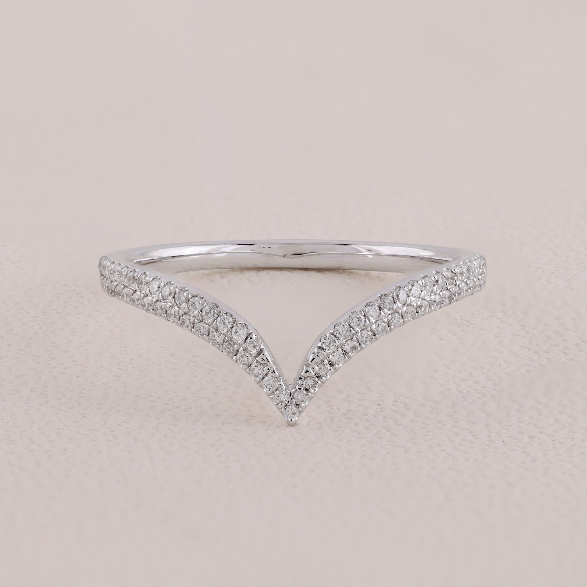 Silver ring with diamond accents on a beige background