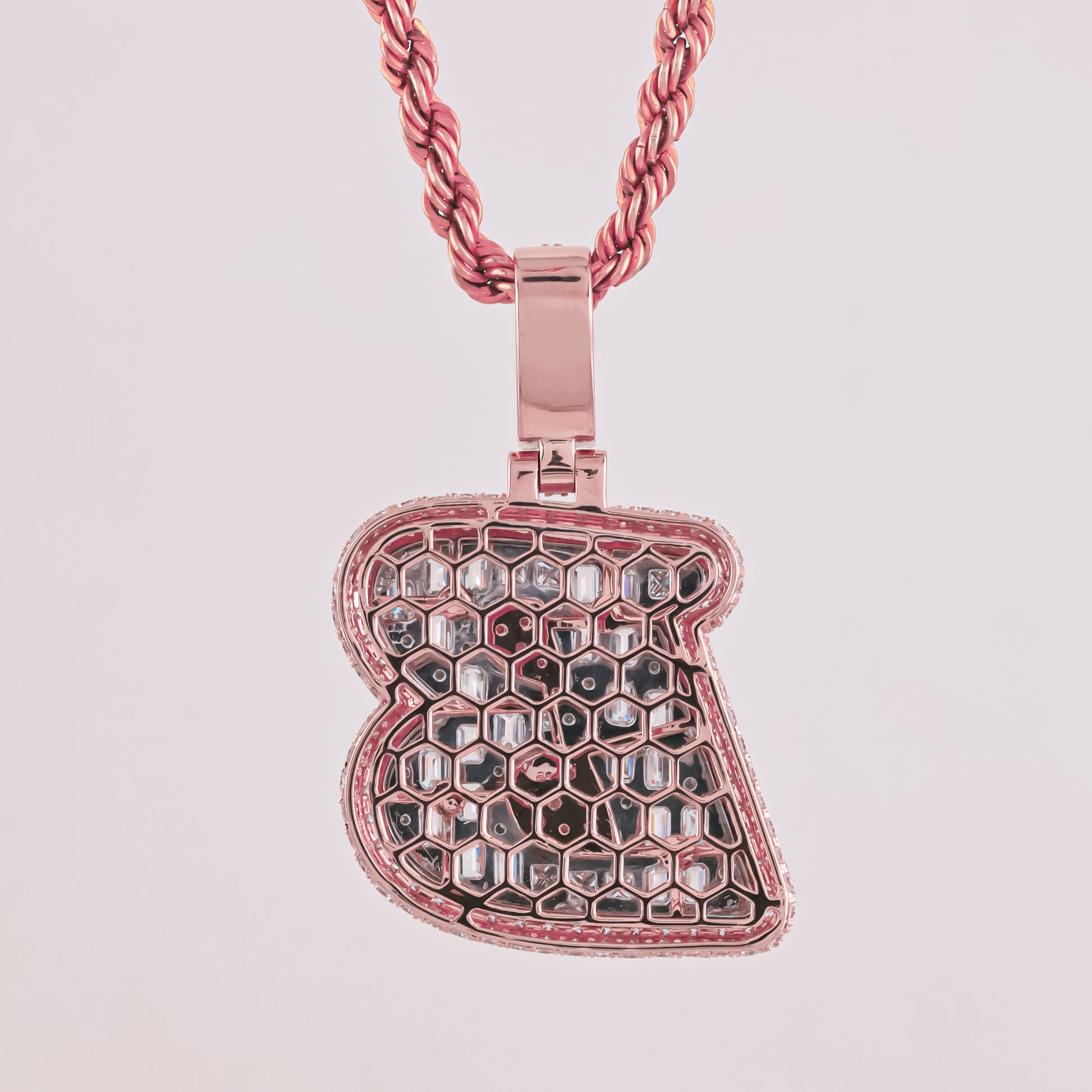 Rose gold honeycomb pendant on a pink chain against a light pink background