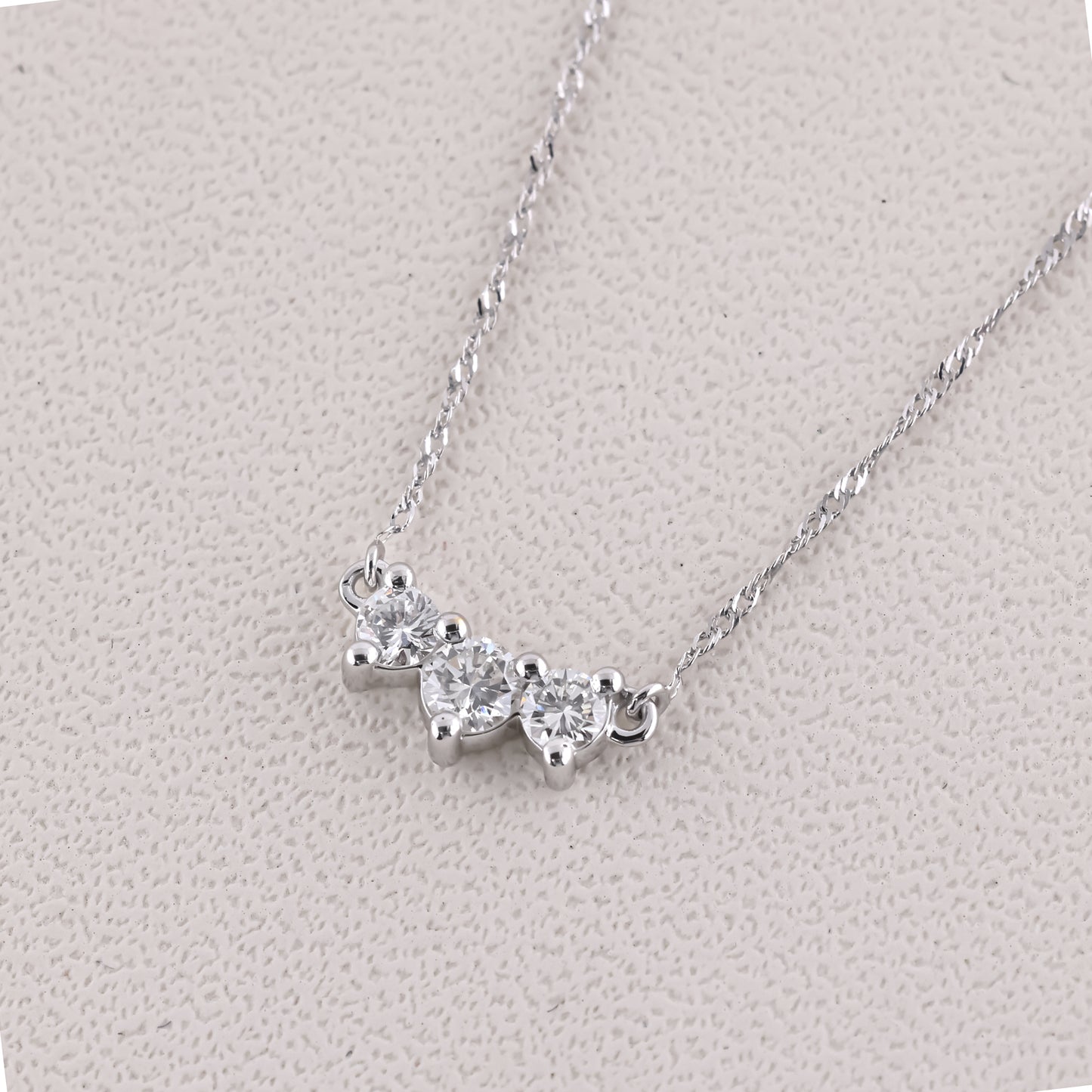 Silver necklace with heart-shaped pendants on a light gray background