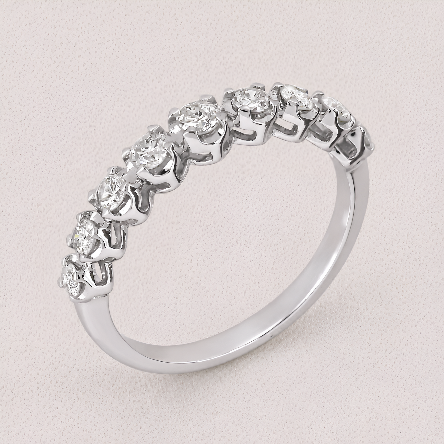 A silver-toned diamond eternity ring with a continuous row of round-cut diamonds set in a polished band, shown on a light textured background.