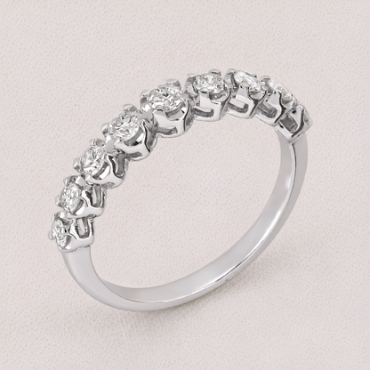 A silver-toned diamond eternity ring with a continuous row of round-cut diamonds set in a polished band, shown on a light textured background.