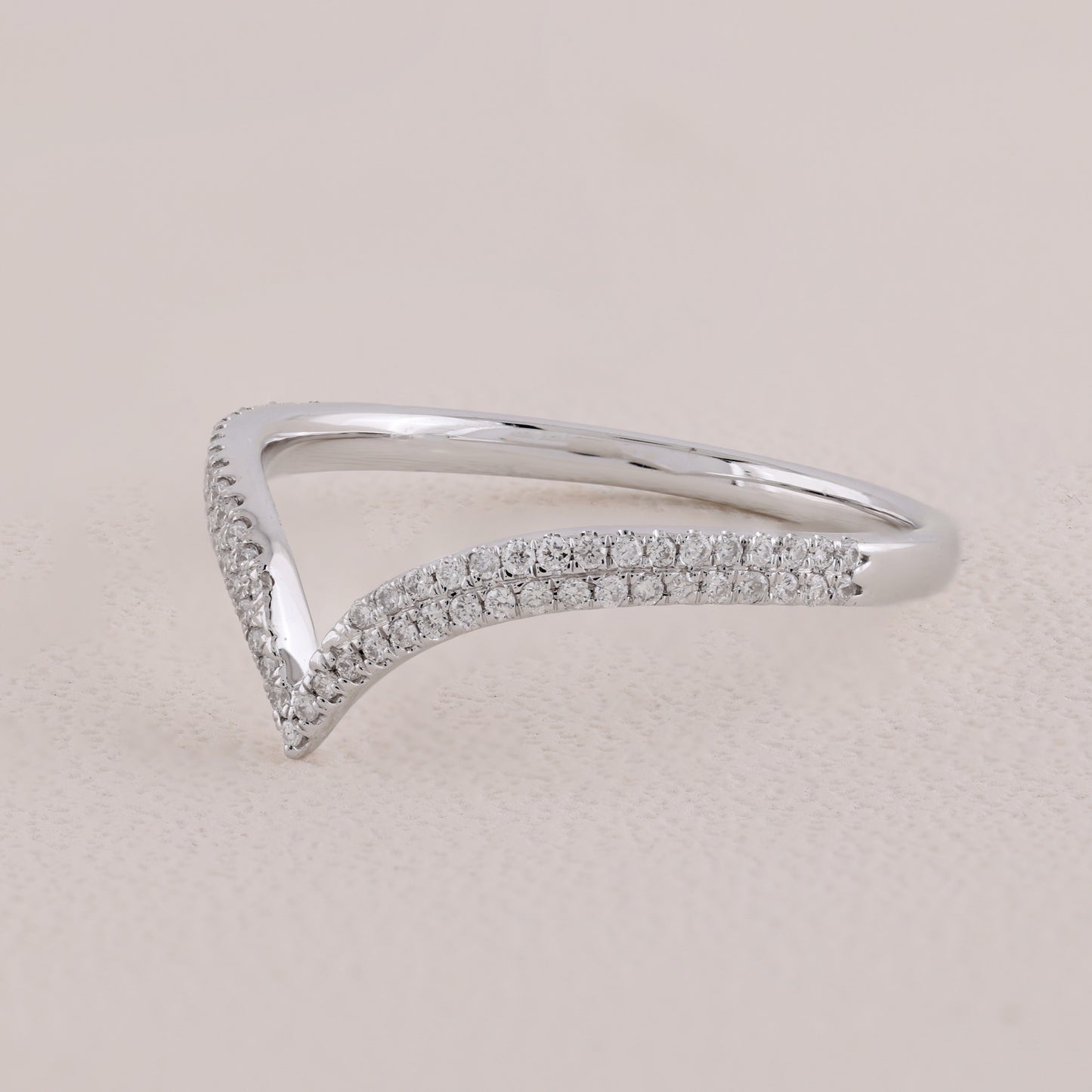 Silver ring with small diamonds on a light beige background