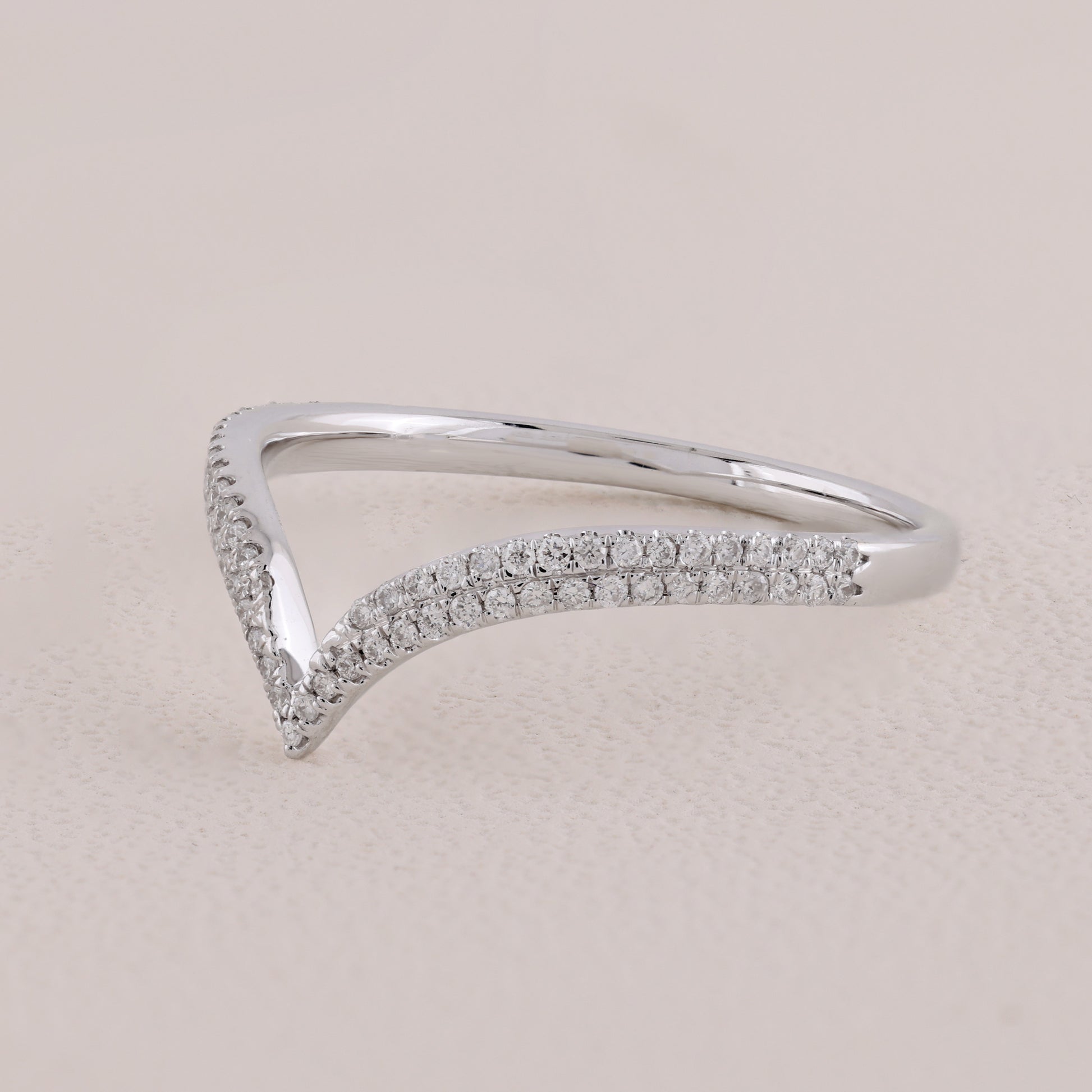 Silver ring with small diamonds on a light beige background