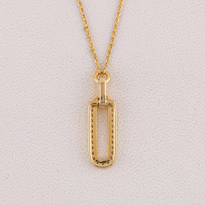 Gold necklace with a rectangular pendant on a light gray background