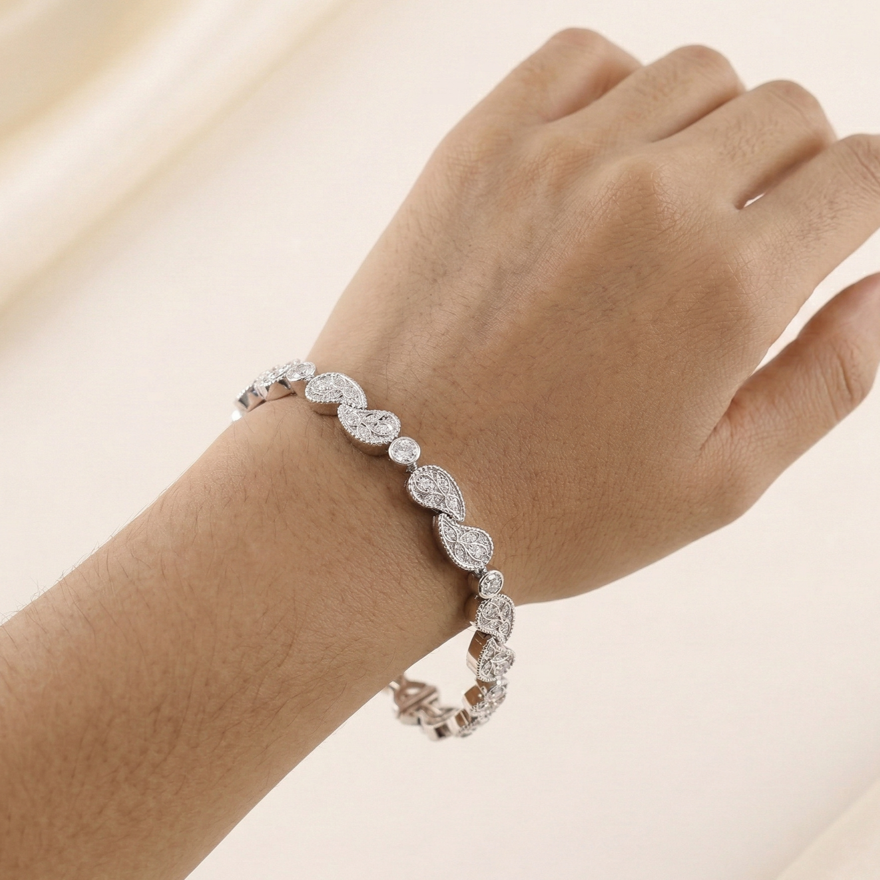 White Gold bracelet with diamond accents on a wrist against a beige background