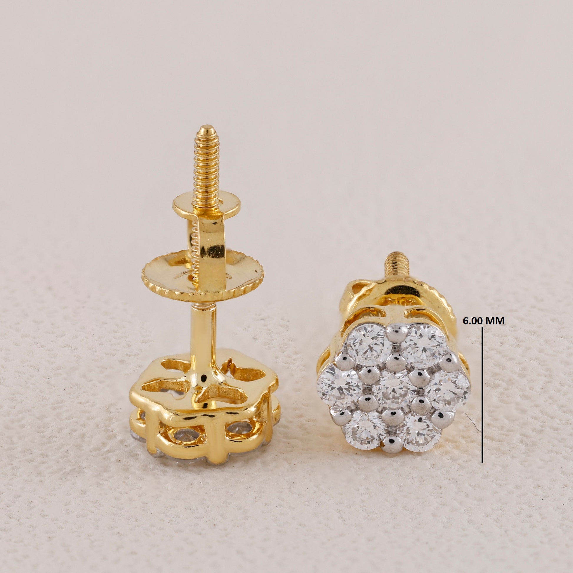 Gold earring studs with diamond cluster design on a light gray background