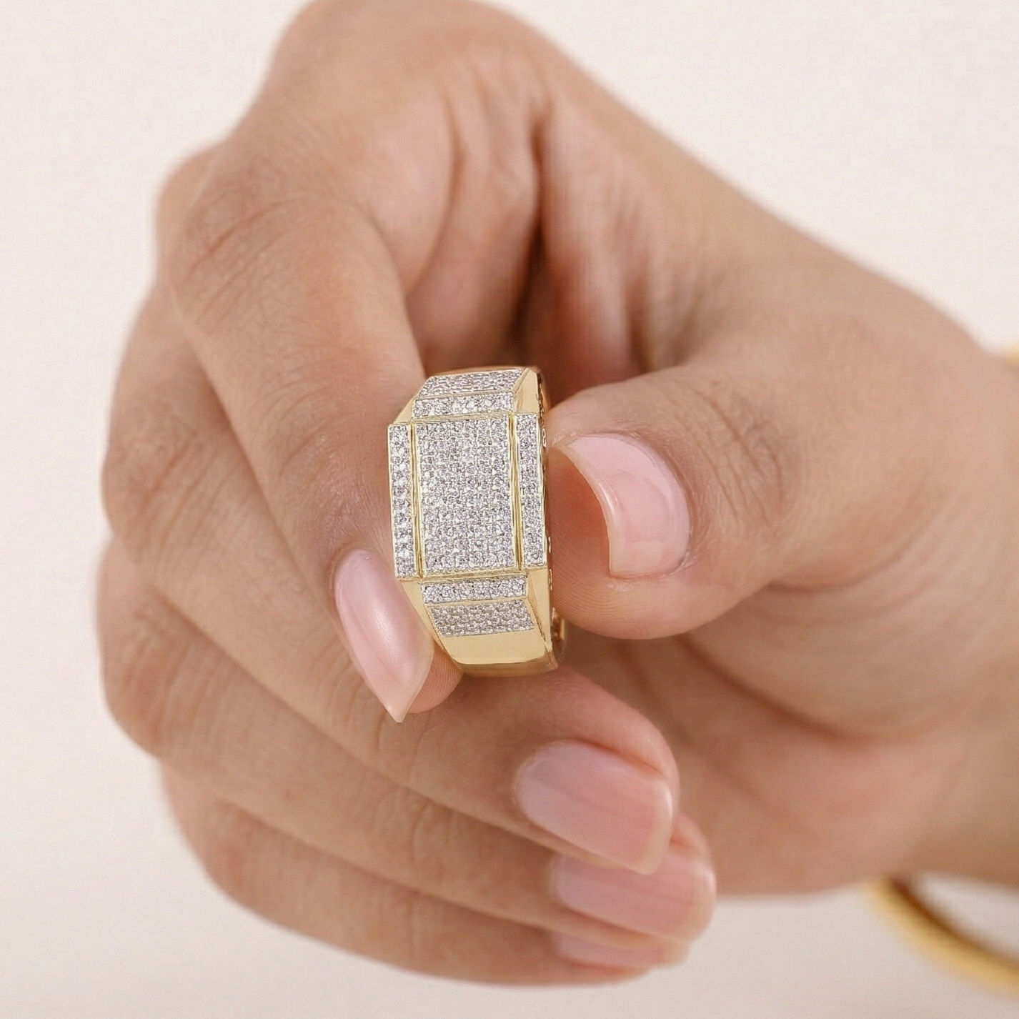 Gold ring with diamonds on a hand against a light background