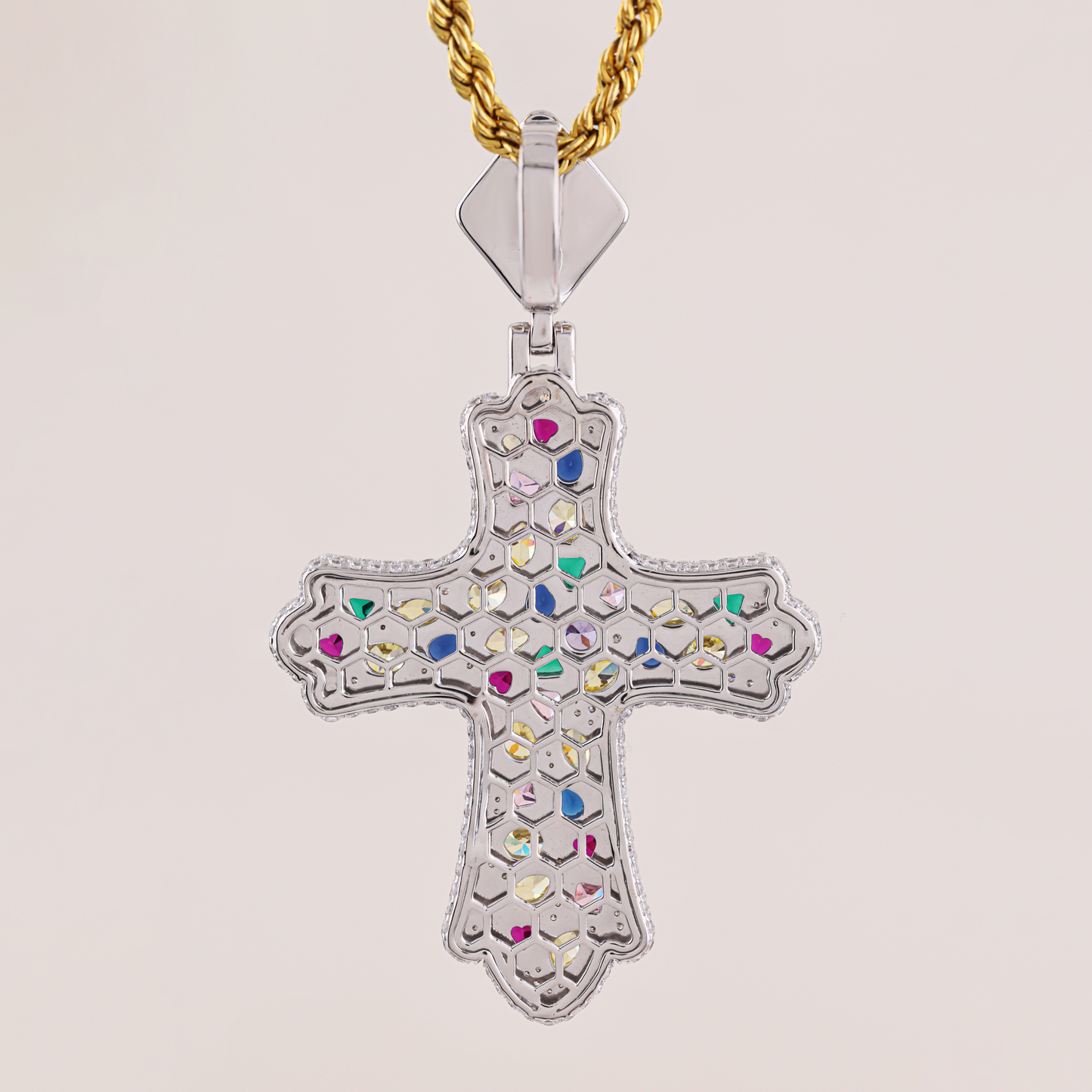 Decorative cross pendant with colorful stones on a gold chain against a light background