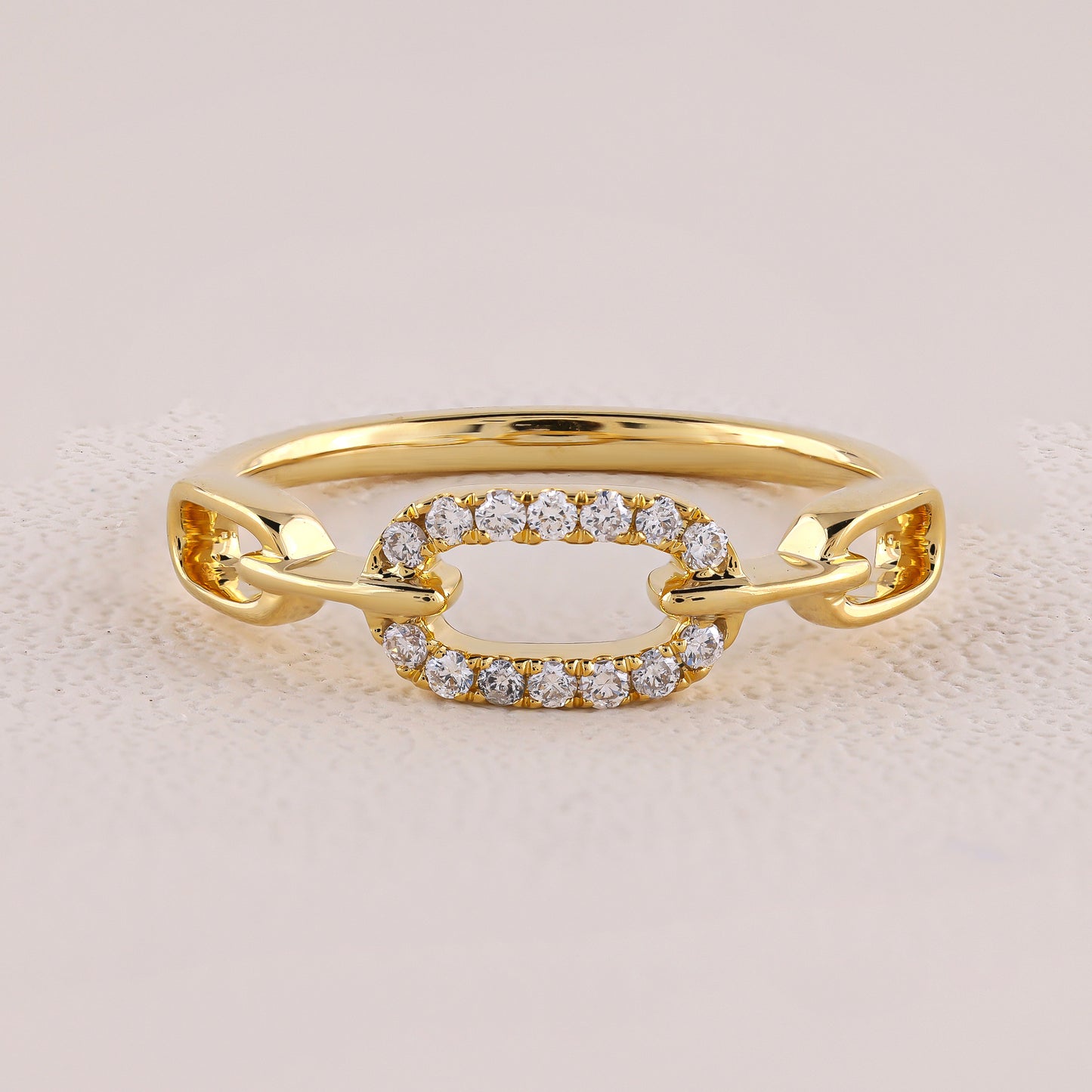 Gold ring with diamond accents on a light pink background