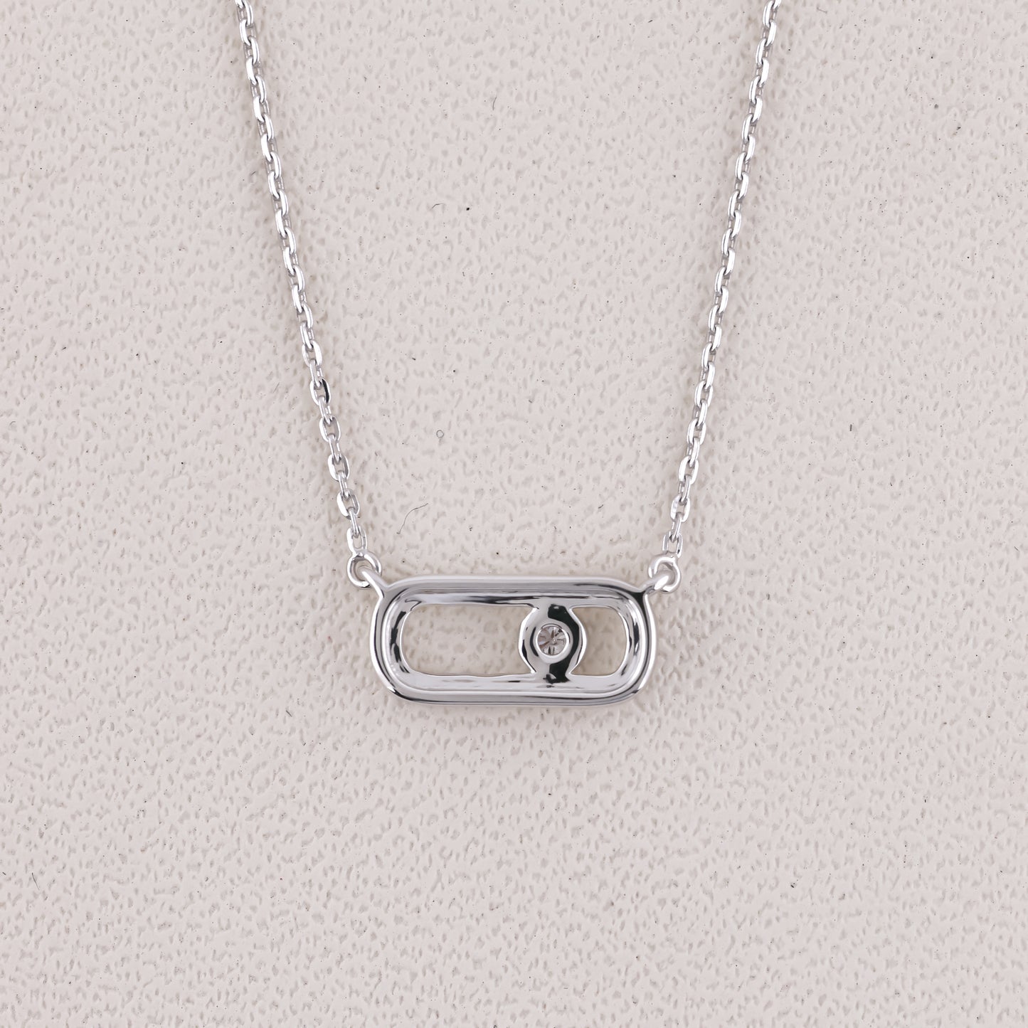 Silver necklace with a rectangular pendant on a light gray background