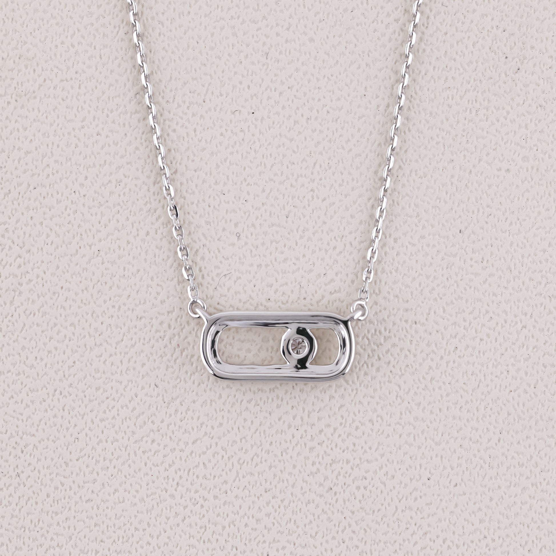 Silver necklace with a rectangular pendant on a light gray background