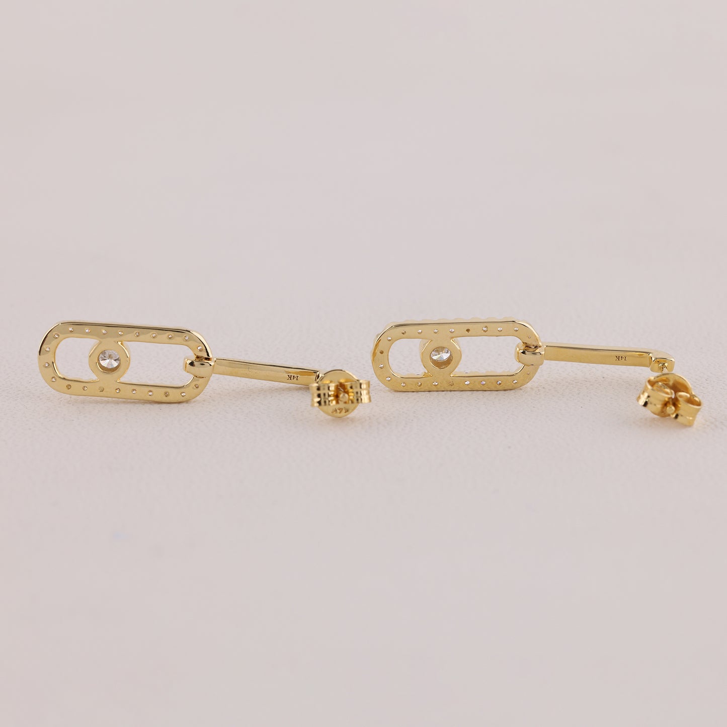 Gold earrings on a light gray background
