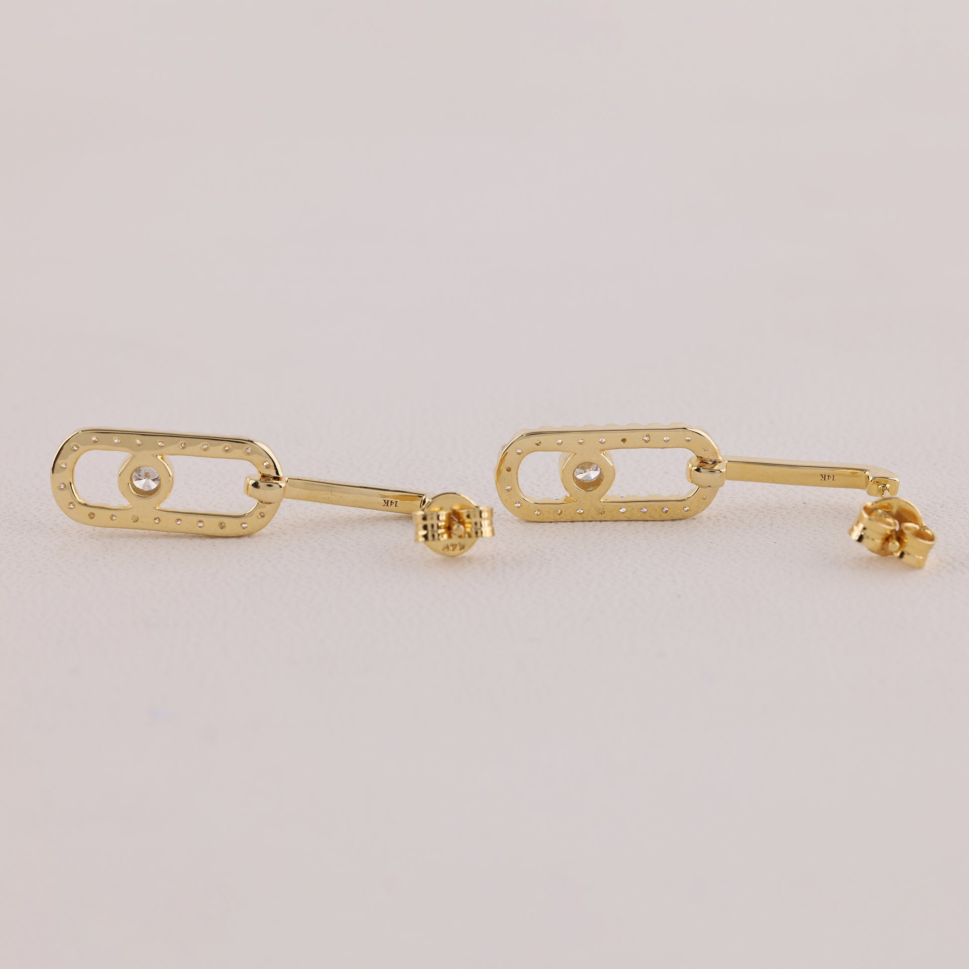 Gold earrings on a light gray background