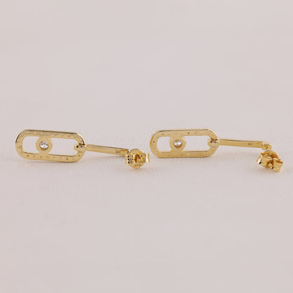 Gold earrings on a light gray background