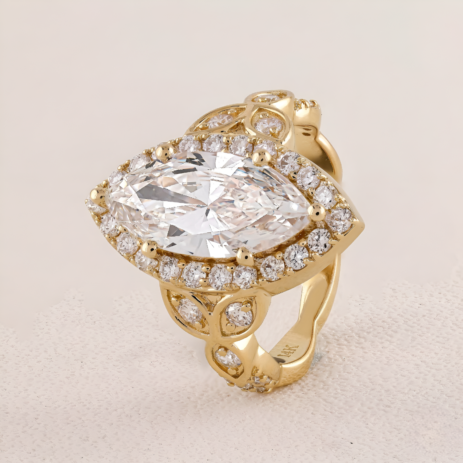 Gold ring with a large diamond and smaller diamonds on a beige background