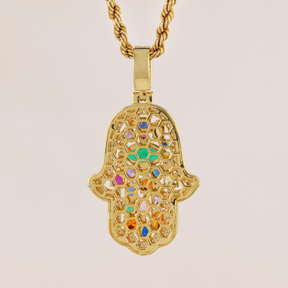 Gold Hamsa pendant with colorful stones on a beige background