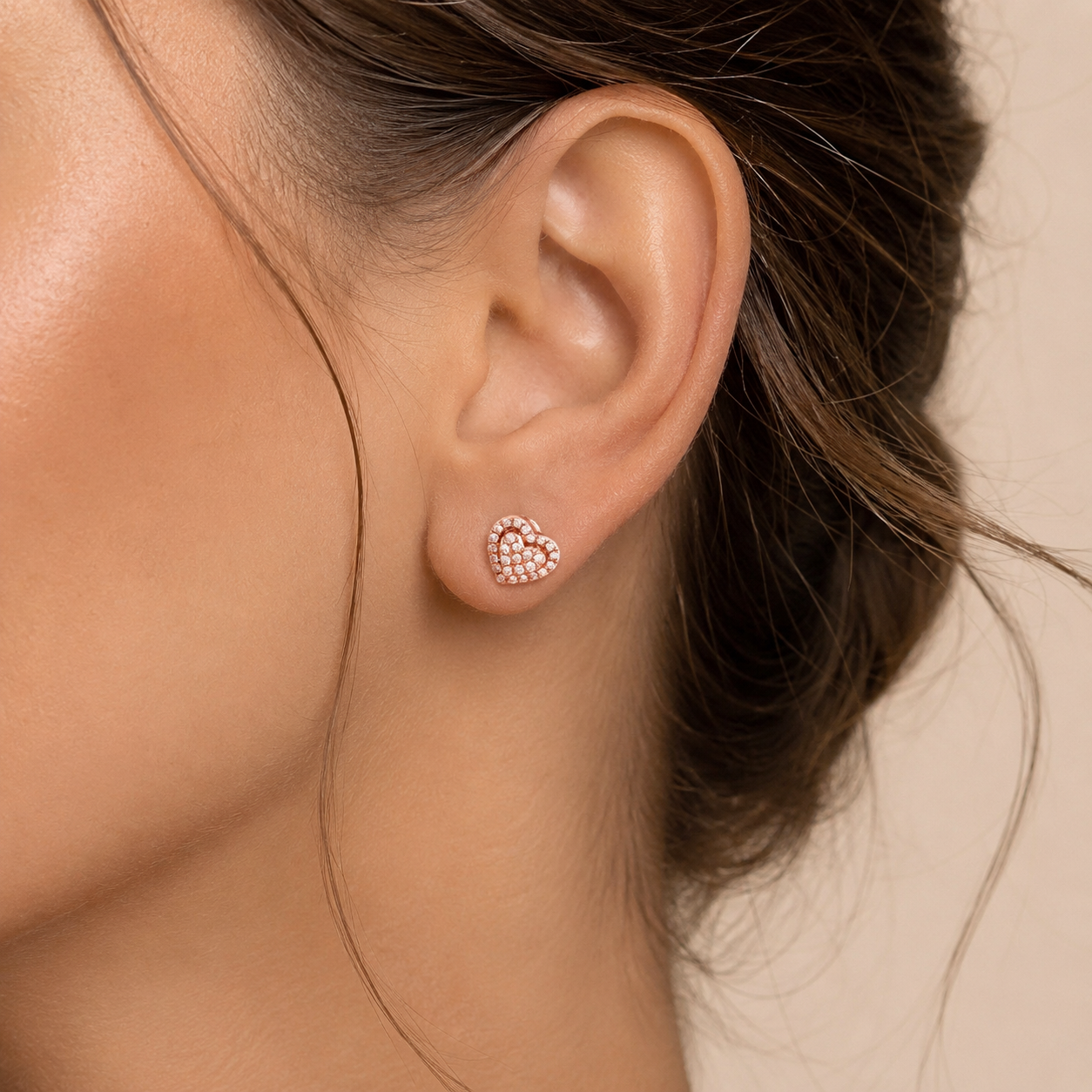 Close-up of an ear wearing a heart-shaped earring with a blurred background
